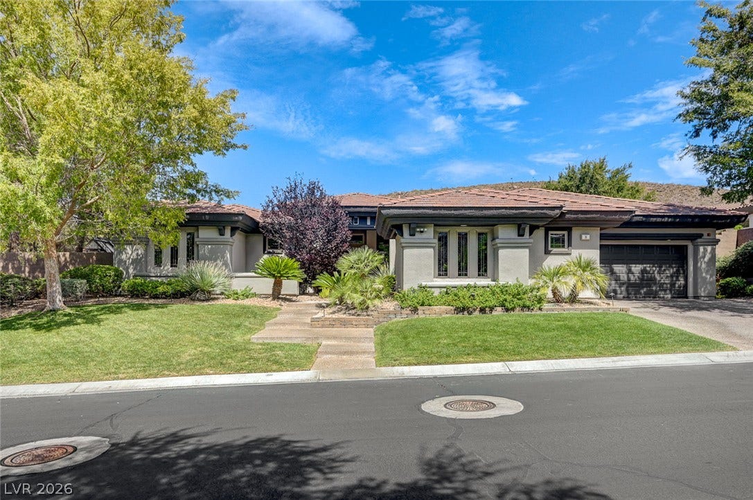 8 Starbrook Drive, Henderson, NV 89052 Manicured lawns flank a concrete path leading to this tile-roofed desert contemporary home.