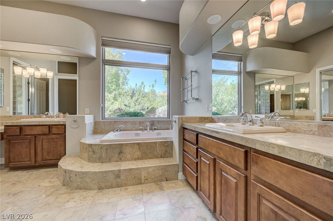 8 Starbrook Drive, Henderson, NV 89052 A spacious bathroom features dual wood vanities, tile flooring, and an elevated soaking tub.