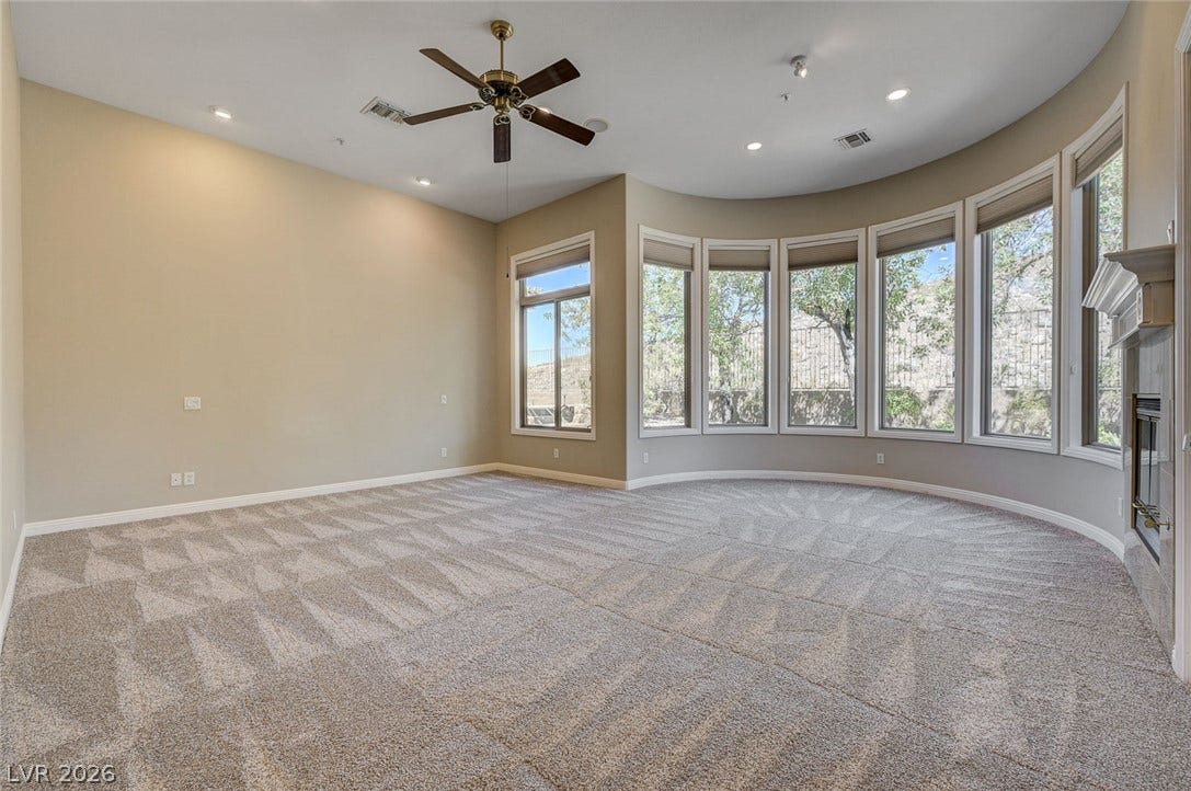 8 Starbrook Drive, Henderson, NV 89052 Plentiful natural light streams through a curved wall of windows onto patterned carpeting.