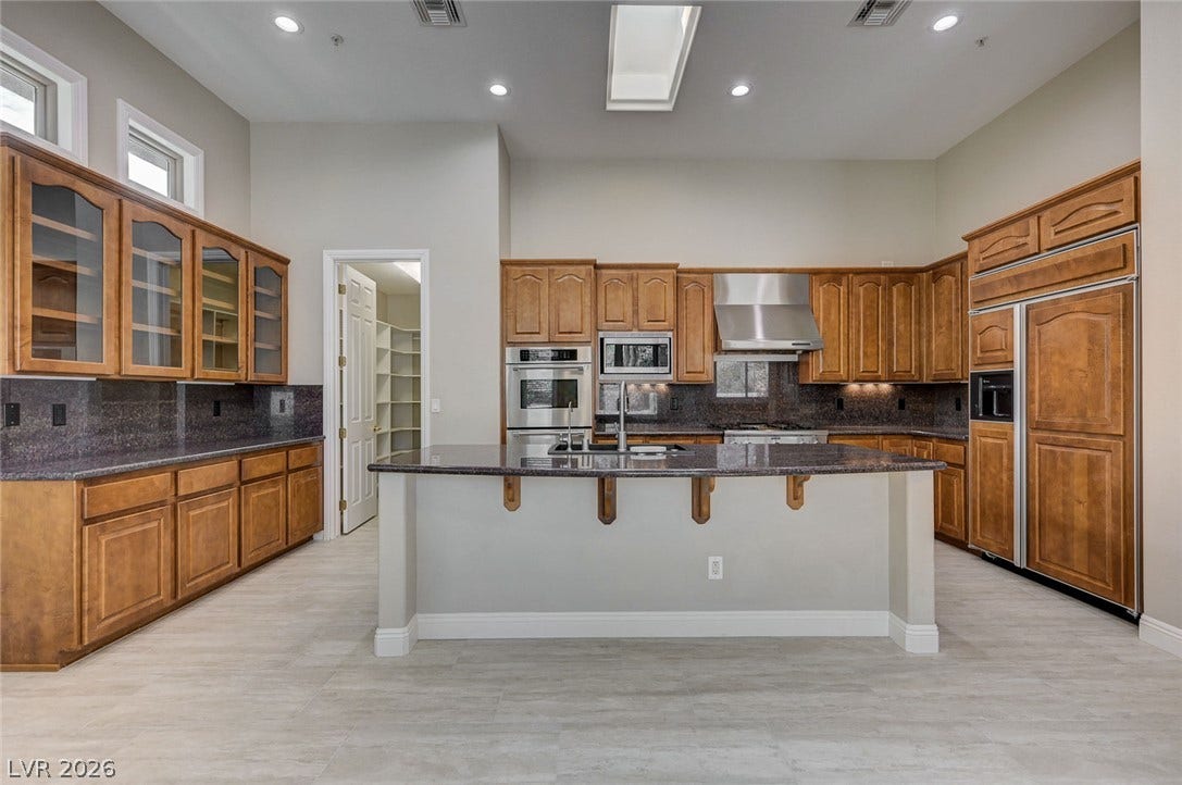 8 Starbrook Drive, Henderson, NV 89052 Rich wood cabinetry and granite countertops anchor this kitchen beneath a central skylight.