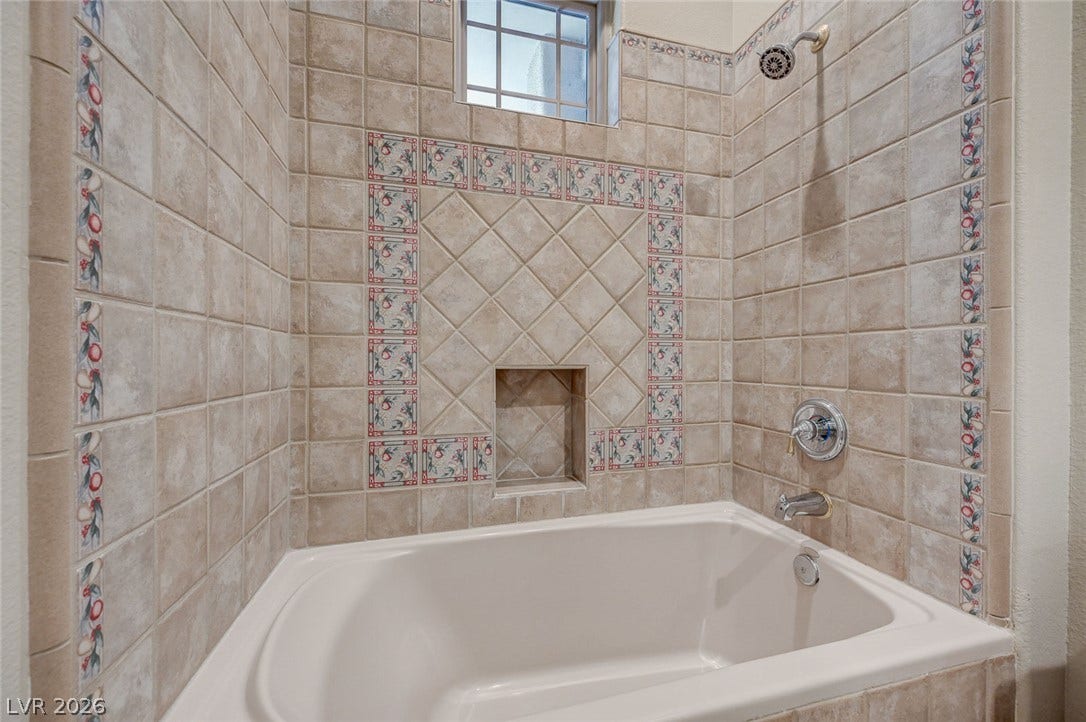 8 Starbrook Drive, Henderson, NV 89052 An alcove bathtub features detailed ceramic tile surrounds with a built-in storage niche.