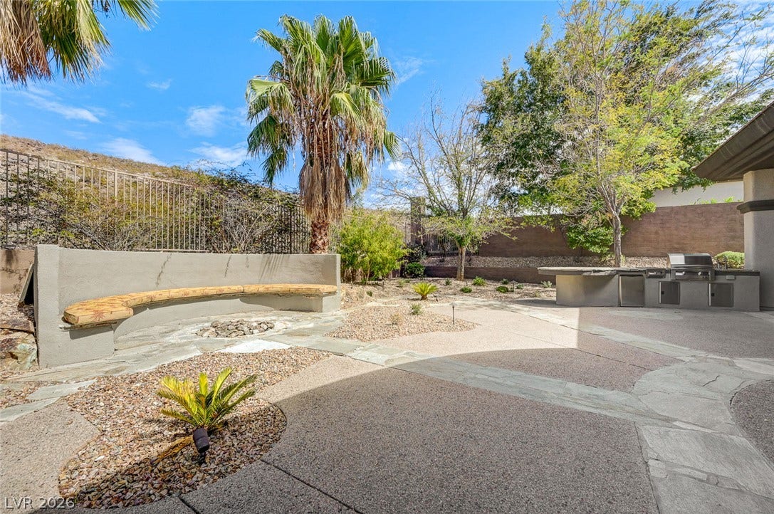 8 Starbrook Drive, Henderson, NV 89052 An expansive paved patio includes a built-in stone bench, fire pit, and outdoor kitchen.
