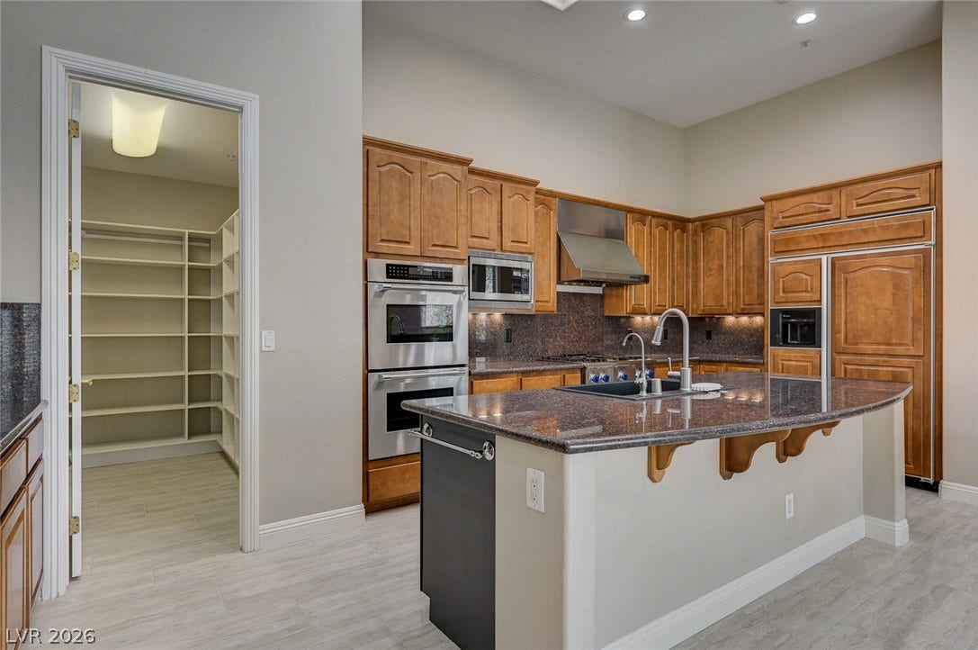 8 Starbrook Drive, Henderson, NV 89052 Rich wood cabinetry and a central island ground this high-ceilinged culinary space near the pantry.
