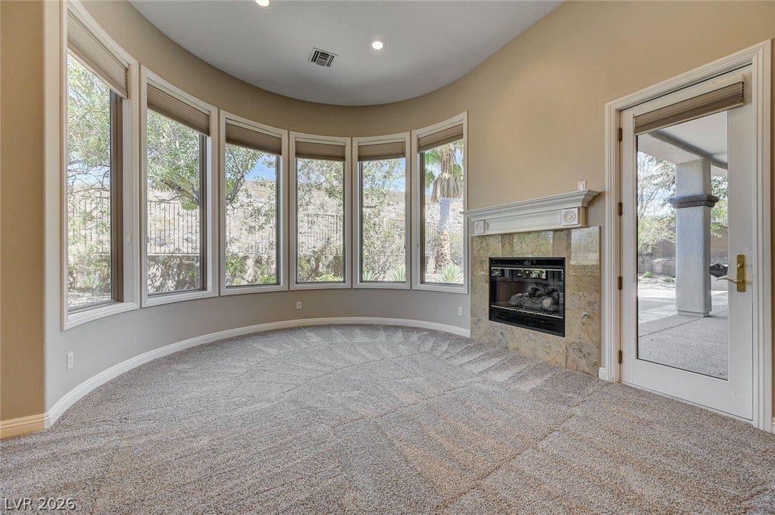 8 Starbrook Drive, Henderson, NV 89052 Plush carpeting and a curved wall of windows define this cozy fireplace-warmed room.