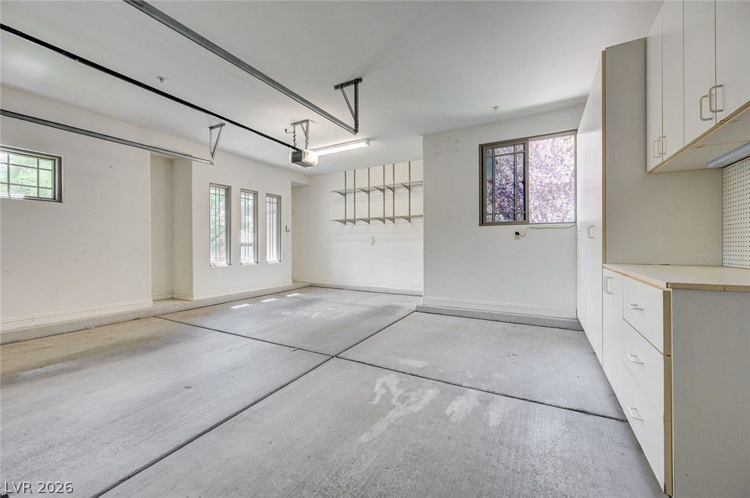 8 Starbrook Drive, Henderson, NV 89052 A spacious garage features durable concrete flooring alongside abundant built-in storage cabinets and shelving.