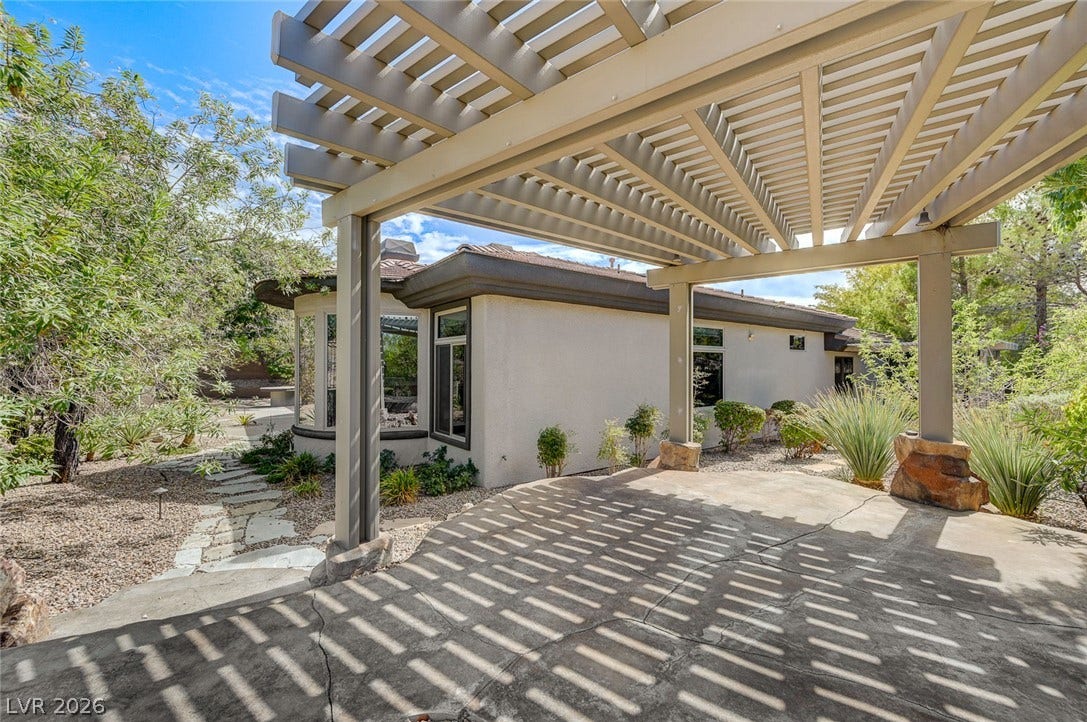 8 Starbrook Drive, Henderson, NV 89052 A spacious concrete patio rests beneath a protective custom pergola overlooking the landscaped backyard.
