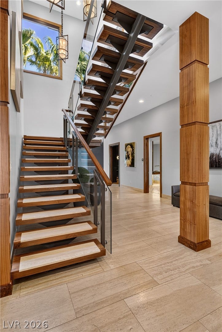 761 Dragon Ridge Drive, Henderson, NV 89012 An architectural open-riser staircase anchors the grand foyer featuring soaring ceilings and natural stone flooring.