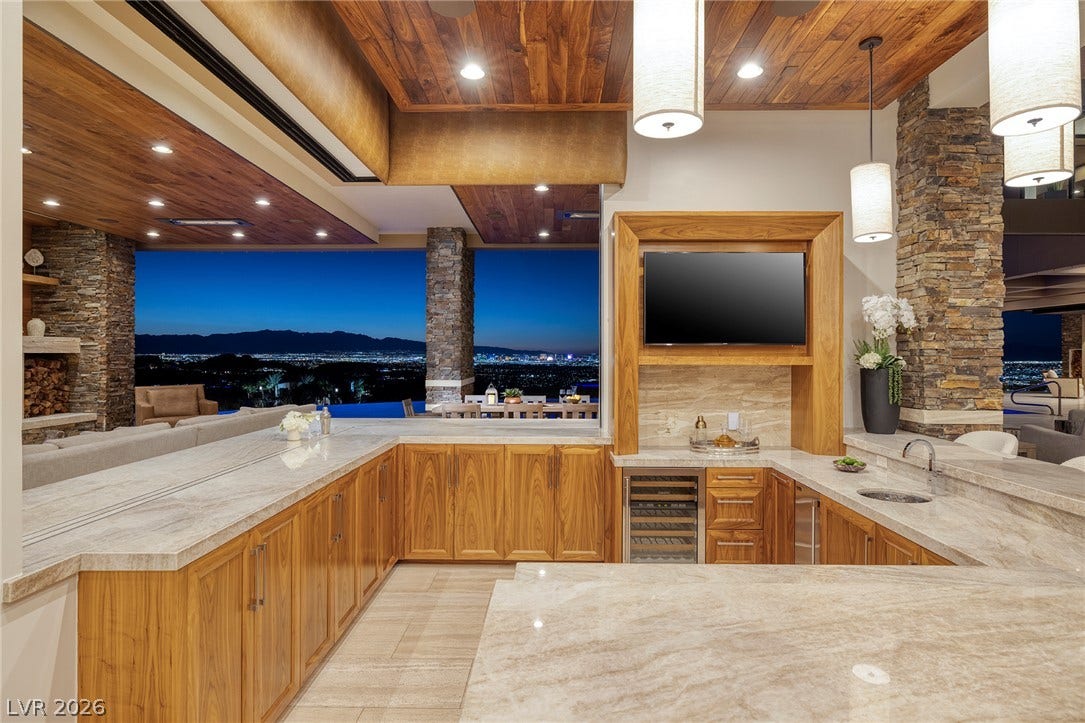 761 Dragon Ridge Drive, Henderson, NV 89012 Rich wood ceilings and polished stone counters frame sweeping evening views from this wet bar.