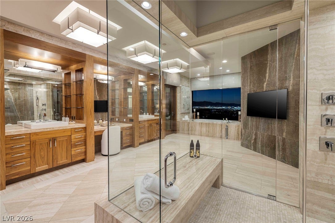 761 Dragon Ridge Drive, Henderson, NV 89012 Gleaming stone finishes and custom wood cabinetry define this luxurious primary bath.