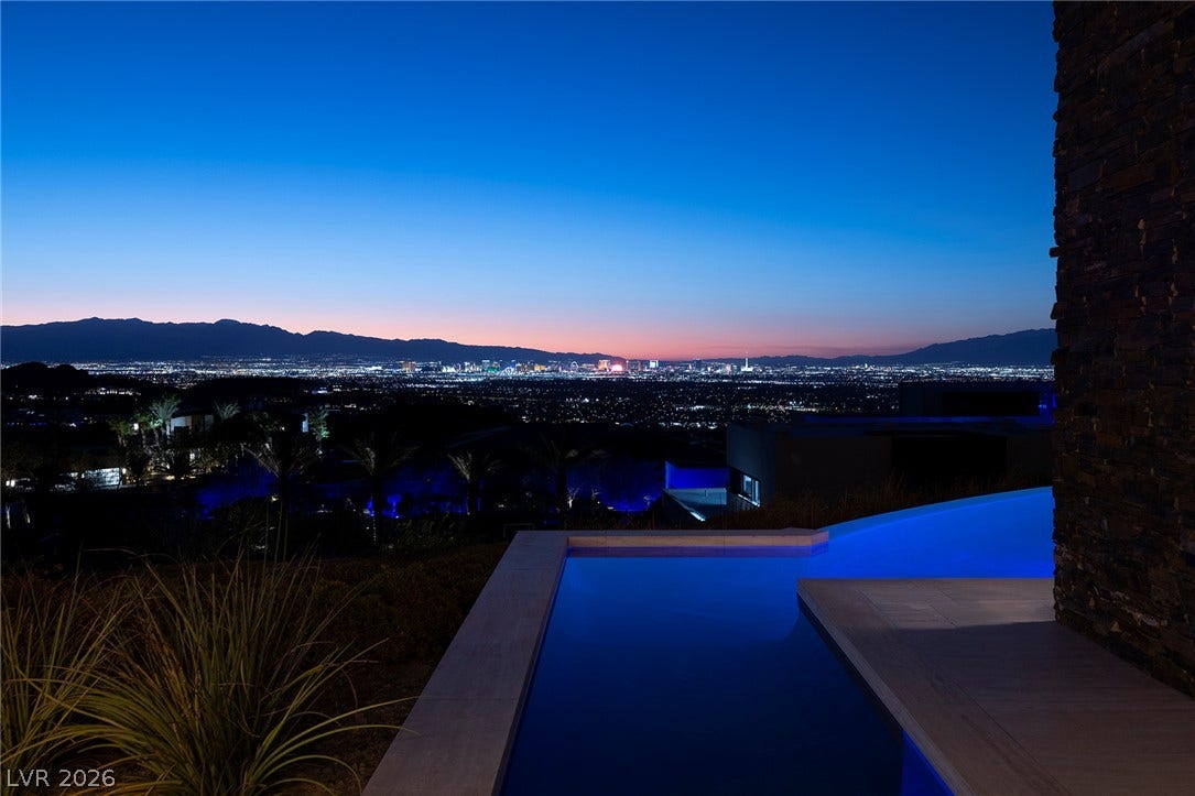 761 Dragon Ridge Drive, Henderson, NV 89012 Glittering city lights shimmer across the horizon beyond a sleek poolside terrace.