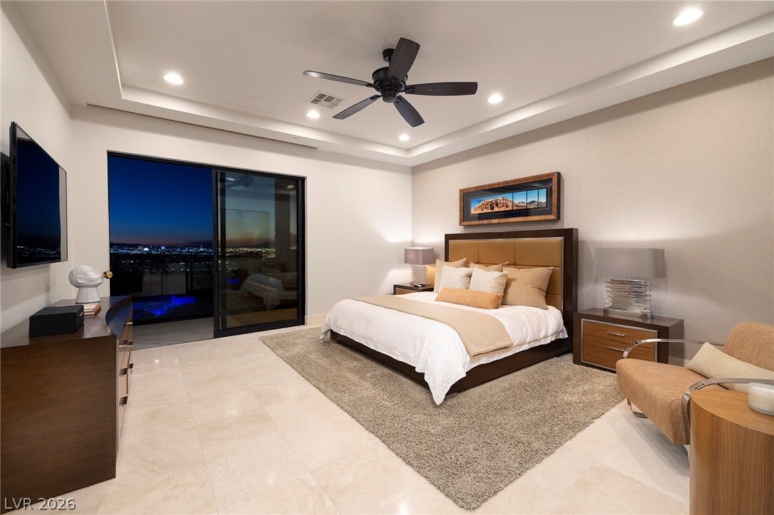 761 Dragon Ridge Drive, Henderson, NV 89012 Gleaming stone tile floors and a recessed tray ceiling define this serene bedroom space.