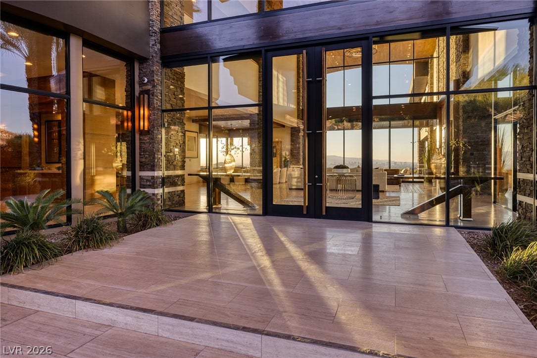 761 Dragon Ridge Drive, Henderson, NV 89012 Massive floor-to-ceiling glass walls frame a grand entryway lined with stone accents.