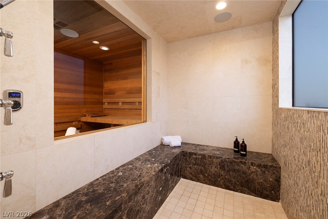 761 Dragon Ridge Drive, Henderson, NV 89012 A spacious stone shower includes a built-in bench adjacent to a glass-walled wood sauna.