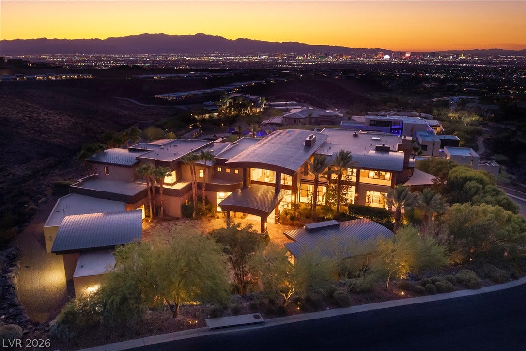 761 Dragon Ridge Drive, Henderson, NV 89012 Dramatic modern architecture commands attention against a backdrop of distant city lights and mountain ridges.