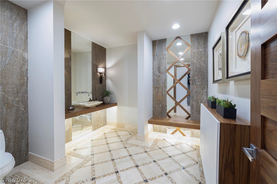 761 Dragon Ridge Drive, Henderson, NV 89012 Ornate custom tile flooring anchors this modern bathroom featuring a floating wood vanity.