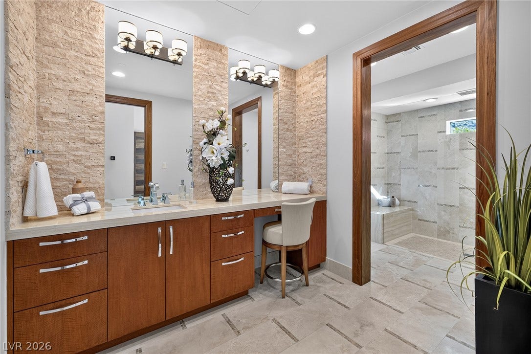 761 Dragon Ridge Drive, Henderson, NV 89012 Fine stonework accents the custom vanity setup adjacent to a spacious walk-in shower area.