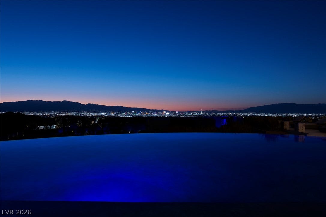 761 Dragon Ridge Drive, Henderson, NV 89012 Glimmering city lights stretch across the horizon beyond a tranquil, illuminated infinity pool.