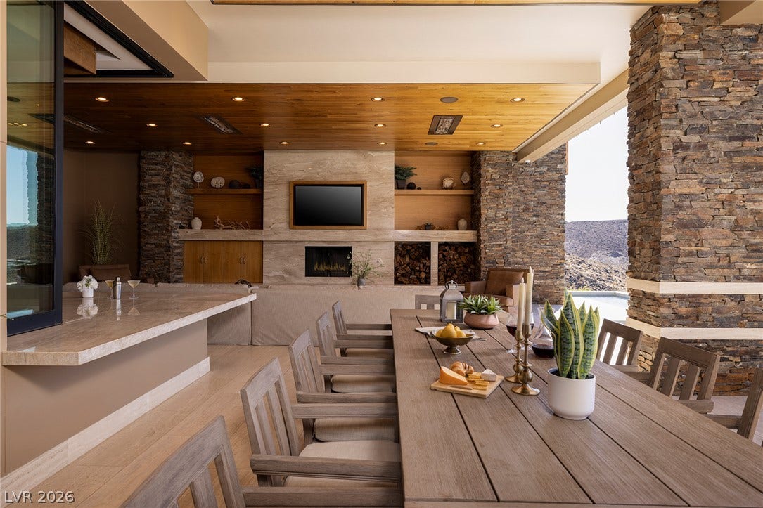 761 Dragon Ridge Drive, Henderson, NV 89012 Incredible indoor-outdoor flow highlights this dining area featuring a linear fireplace and stone accent walls.