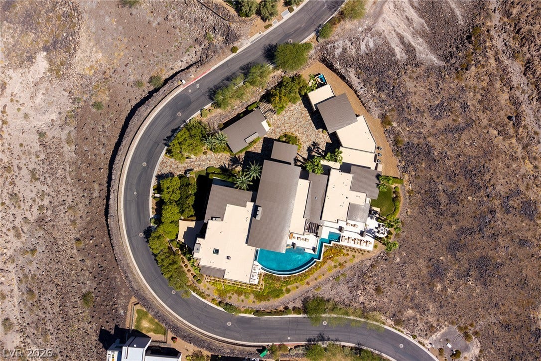 761 Dragon Ridge Drive, Henderson, NV 89012 An aerial perspective showcases the curved design and modern desert architecture of this private hillside estate.