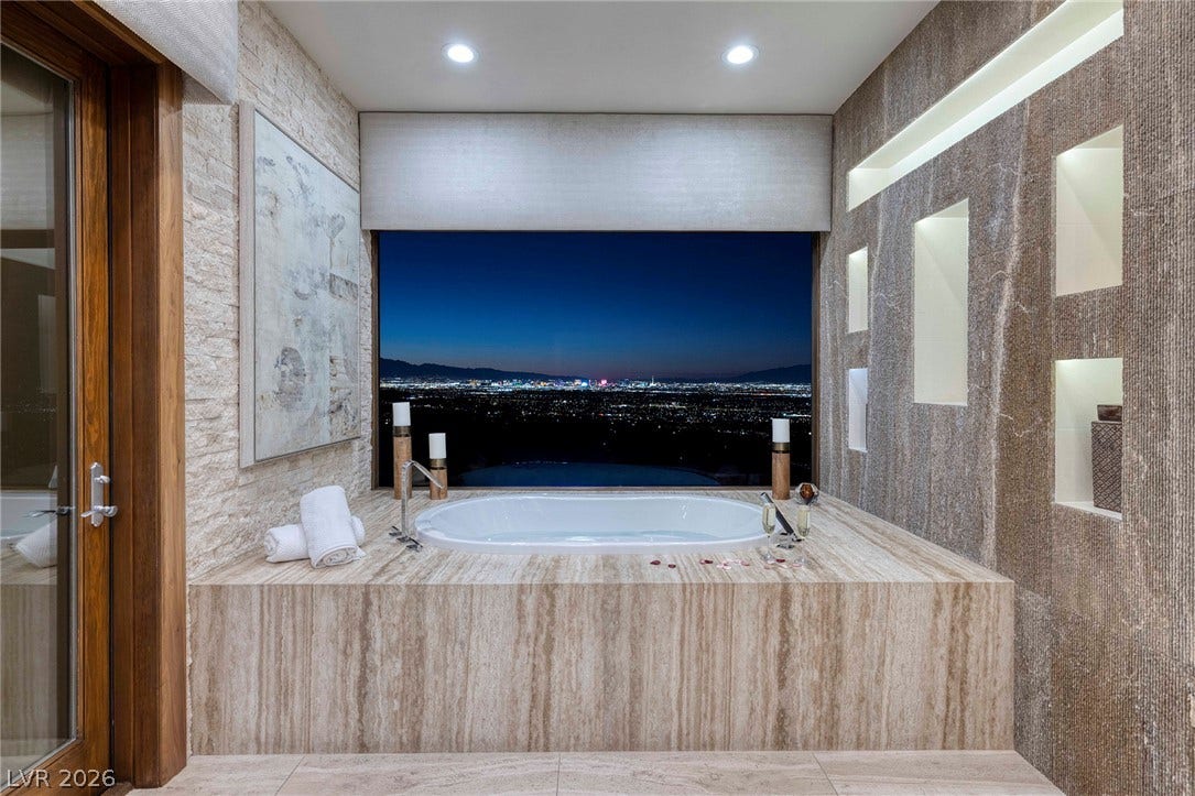 761 Dragon Ridge Drive, Henderson, NV 89012 A deep soaking tub overlooks glittering city skyline views through a massive picture window.