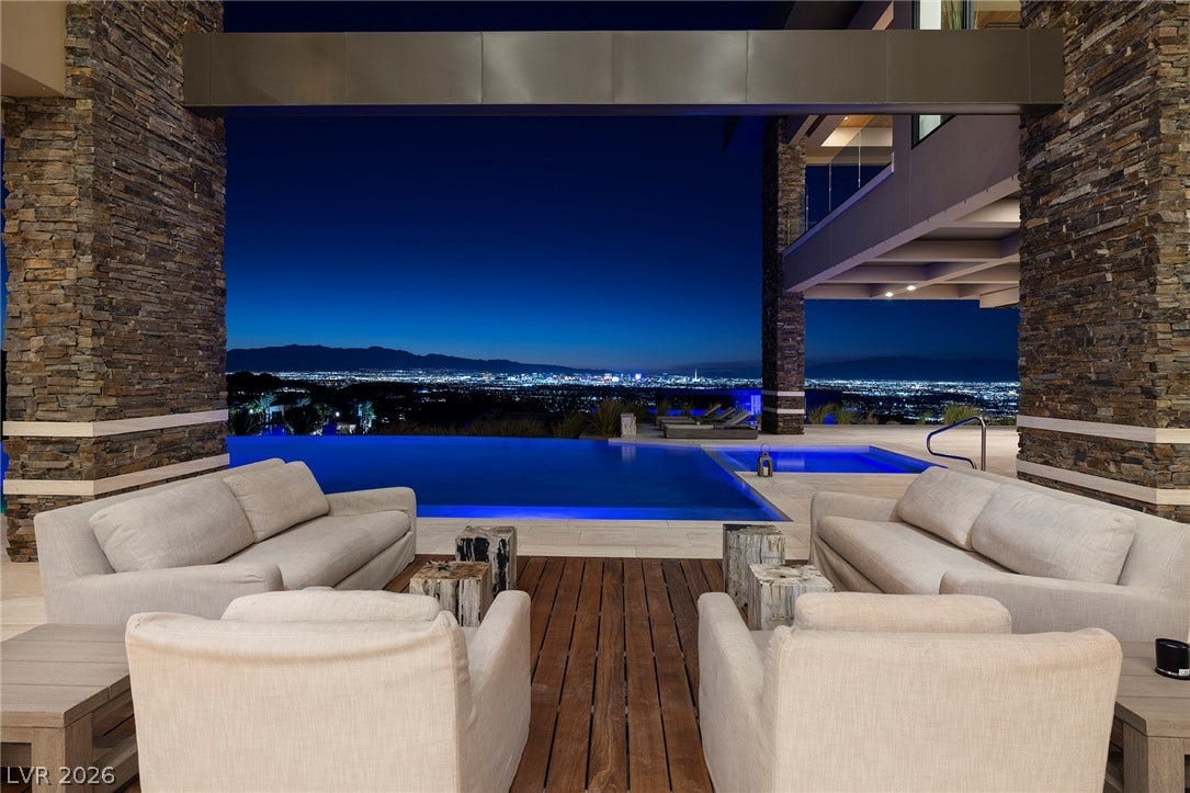 761 Dragon Ridge Drive, Henderson, NV 89012 Panoramic city views frame the covered stone patio alongside an infinity-edge pool.
