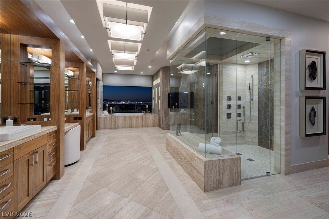 761 Dragon Ridge Drive, Henderson, NV 89012 Rich wood cabinetry and patterned tile floors define this contemporary primary bath oasis.