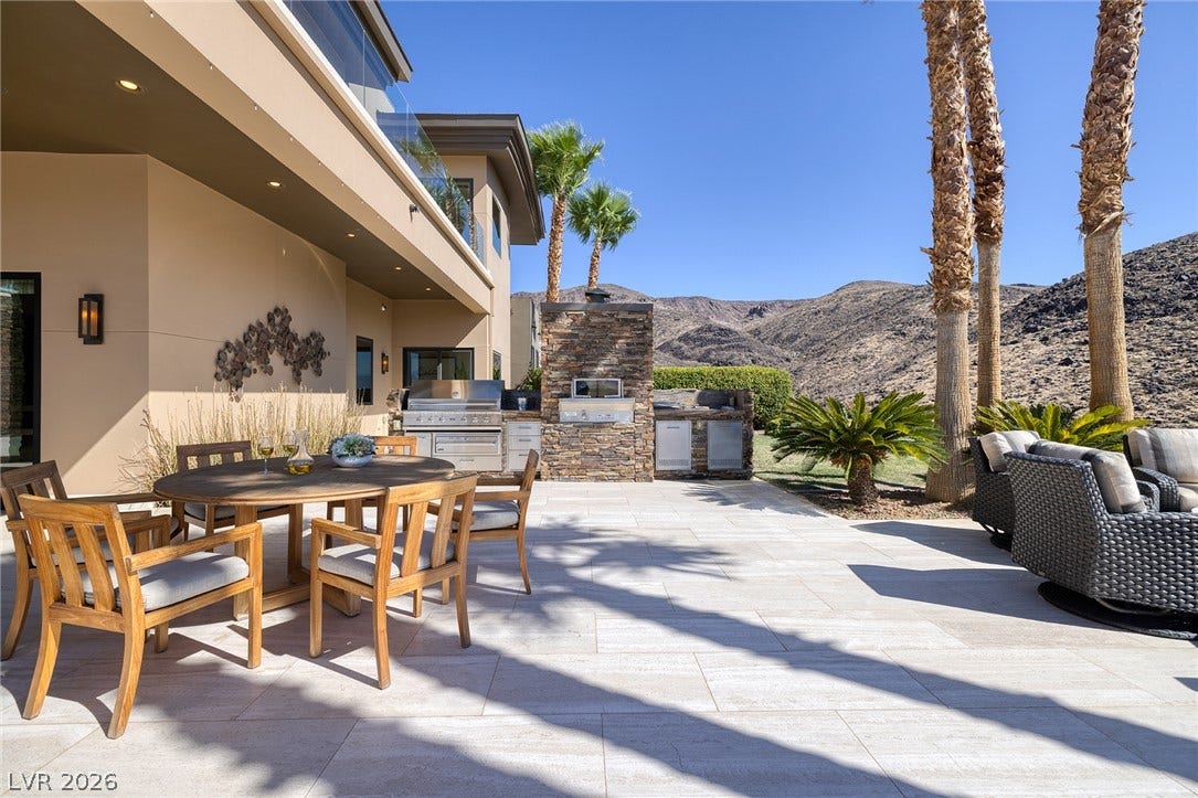 761 Dragon Ridge Drive, Henderson, NV 89012 An outdoor kitchen and dining patio overlook majestic mountain ridges under clear blue skies.