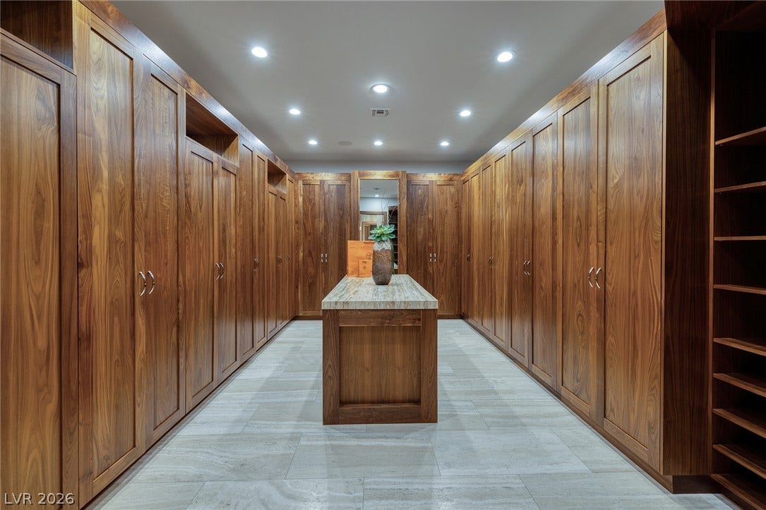 761 Dragon Ridge Drive, Henderson, NV 89012 Rich wood built-ins and a stone-topped island define this spacious wardrobe area.