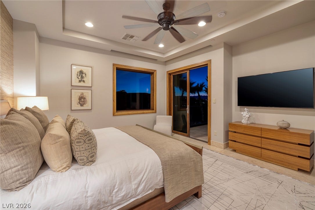 761 Dragon Ridge Drive, Henderson, NV 89012 A tray ceiling and glass sliding doors framing outdoor views define this modern bedroom.