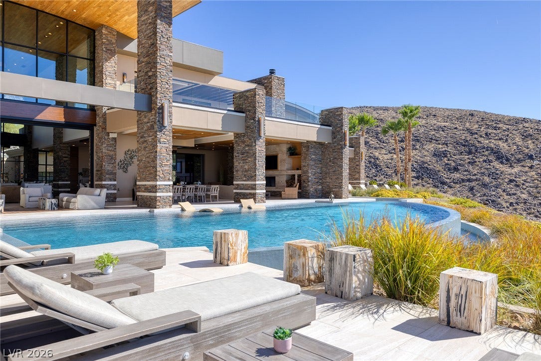 761 Dragon Ridge Drive, Henderson, NV 89012 An infinity pool complements the modern stone columns and expansive glass walls of this desert estate.