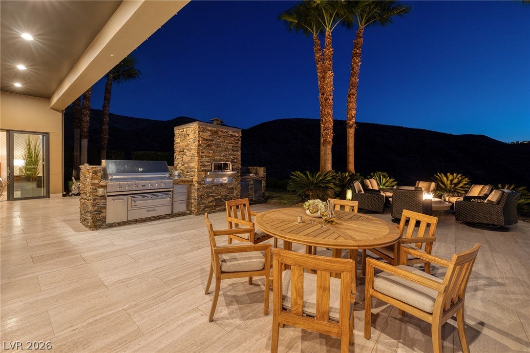761 Dragon Ridge Drive, Henderson, NV 89012 An expansive tiled patio features a stone-clad outdoor kitchen framed by dramatic mountain backdrops.