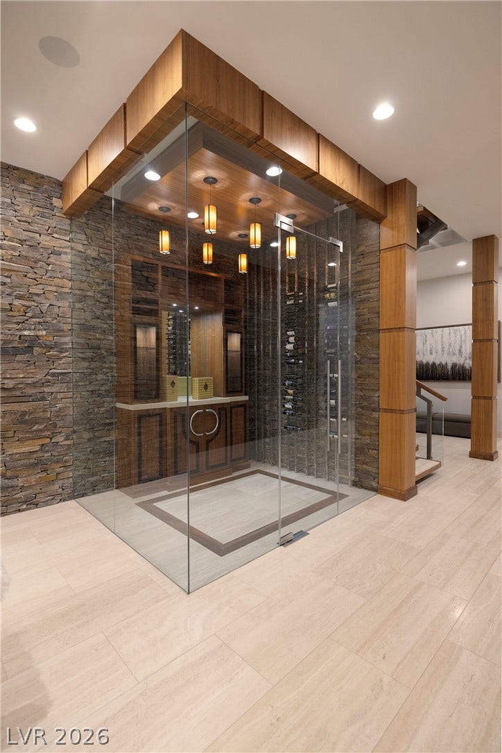 761 Dragon Ridge Drive, Henderson, NV 89012 Stacked stone walls frame a modern glass-enclosed wine room with custom wood accents.