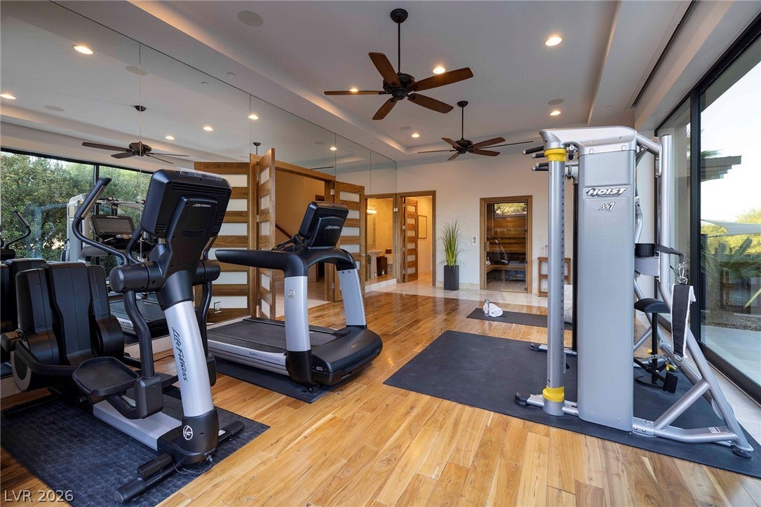 761 Dragon Ridge Drive, Henderson, NV 89012 Rich hardwood flooring and floor-to-ceiling glass doors define this architectural home fitness space.