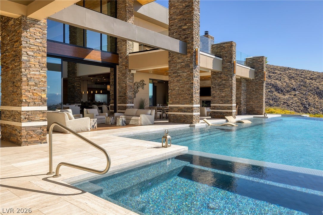 761 Dragon Ridge Drive, Henderson, NV 89012 Massive stone pillars frame the expansive outdoor living spaces alongside a sparkling swimming pool.