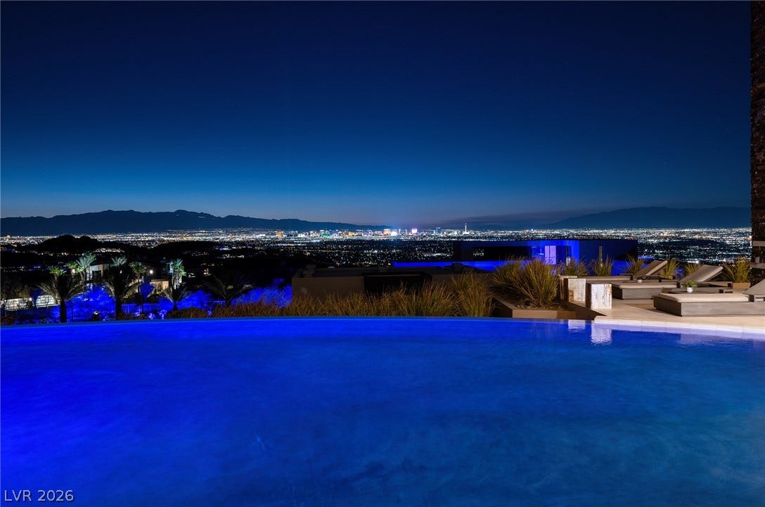761 Dragon Ridge Drive, Henderson, NV 89012 Glimmering city lights frame the horizon beyond a sleek infinity edge pool.