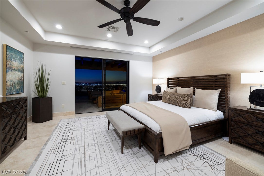 761 Dragon Ridge Drive, Henderson, NV 89012 A tray ceiling and sliding glass doors framing city views enhance this principal bedroom suite.