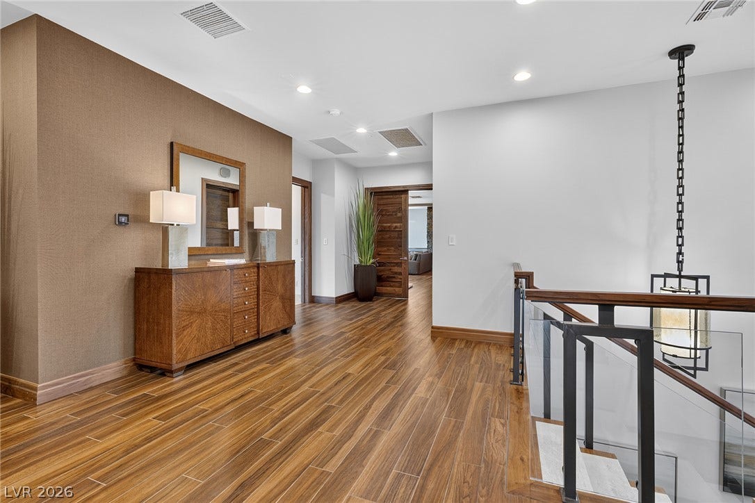 761 Dragon Ridge Drive, Henderson, NV 89012 Rich wood-look flooring guides the eye through this upper-level landing past a modern glass staircase.