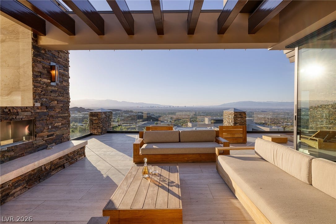 761 Dragon Ridge Drive, Henderson, NV 89012 A spacious stone-tiled patio showcases a striking wood-beamed ceiling and a cozy stone fireplace.