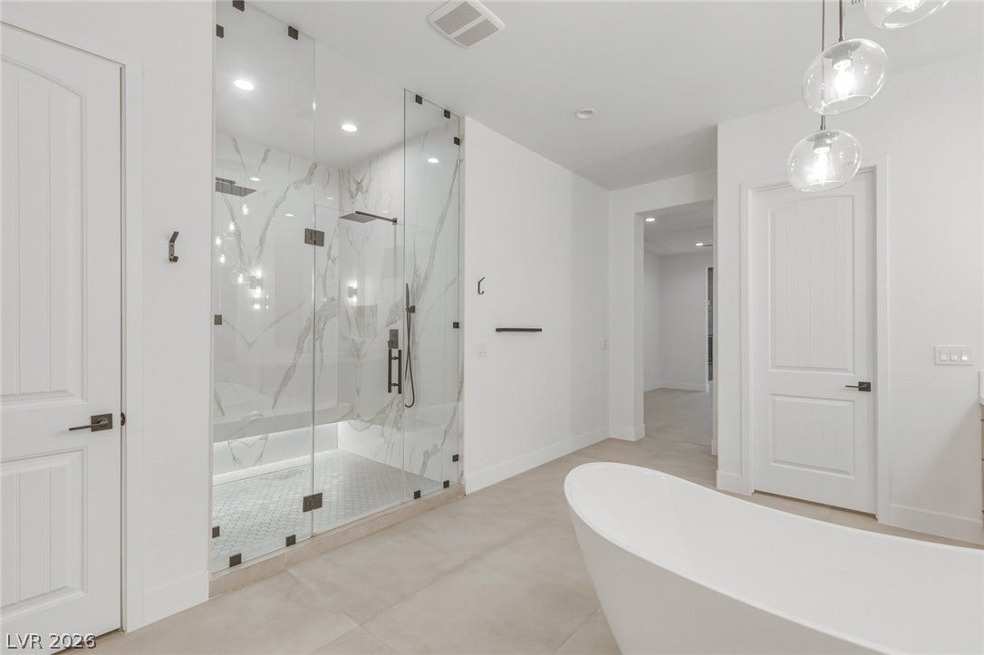 4078 San Franchesca Court, Las Vegas, NV 89141 A well-appointed bath features a spacious glass-enclosed shower alongside a free-standing soaking tub.