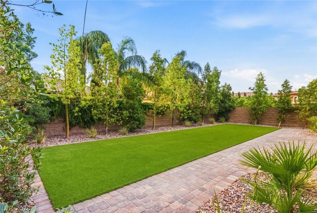 4078 San Franchesca Court, Las Vegas, NV 89141 A private yard with lush artificial turf and paver pathways, bordered by verdant landscaping.