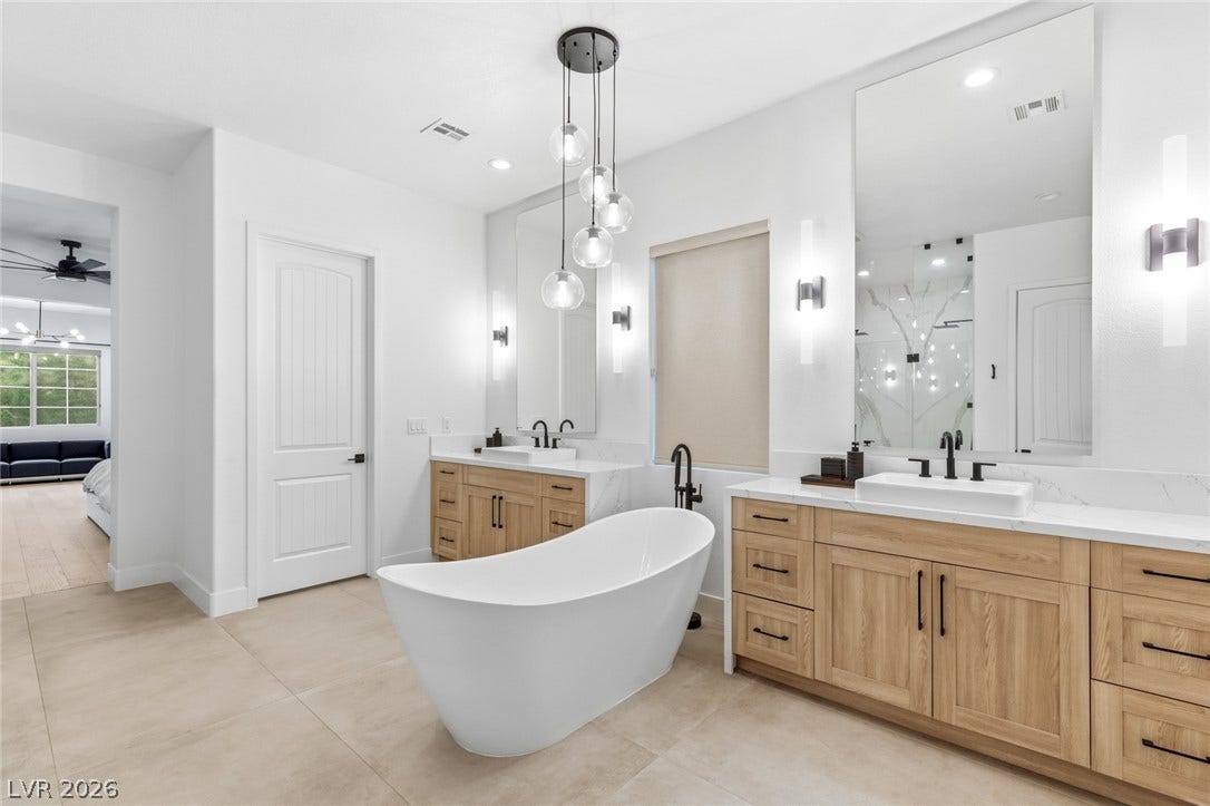 4078 San Franchesca Court, Las Vegas, NV 89141 A spacious bathroom features a freestanding soaking tub and dual vanities, perfect for unwinding.
