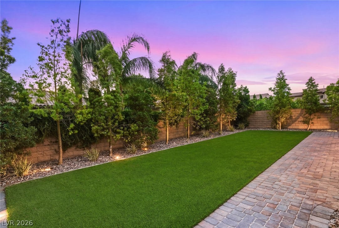4078 San Franchesca Court, Las Vegas, NV 89141 A neatly manicured lawn with elegant paver pathways provides a serene outdoor retreat under a vibrant sunset.