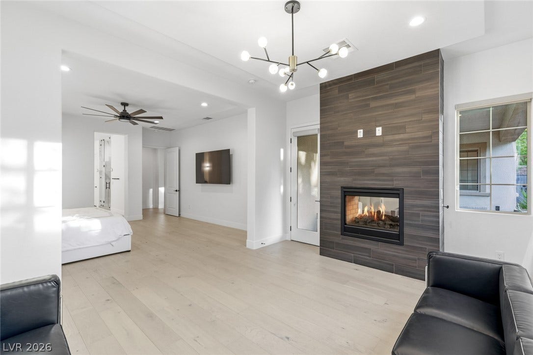 4078 San Franchesca Court, Las Vegas, NV 89141 A refined bedroom with a statement fireplace and light hardwood flooring, offering a perfect blend of warmth and elegance.