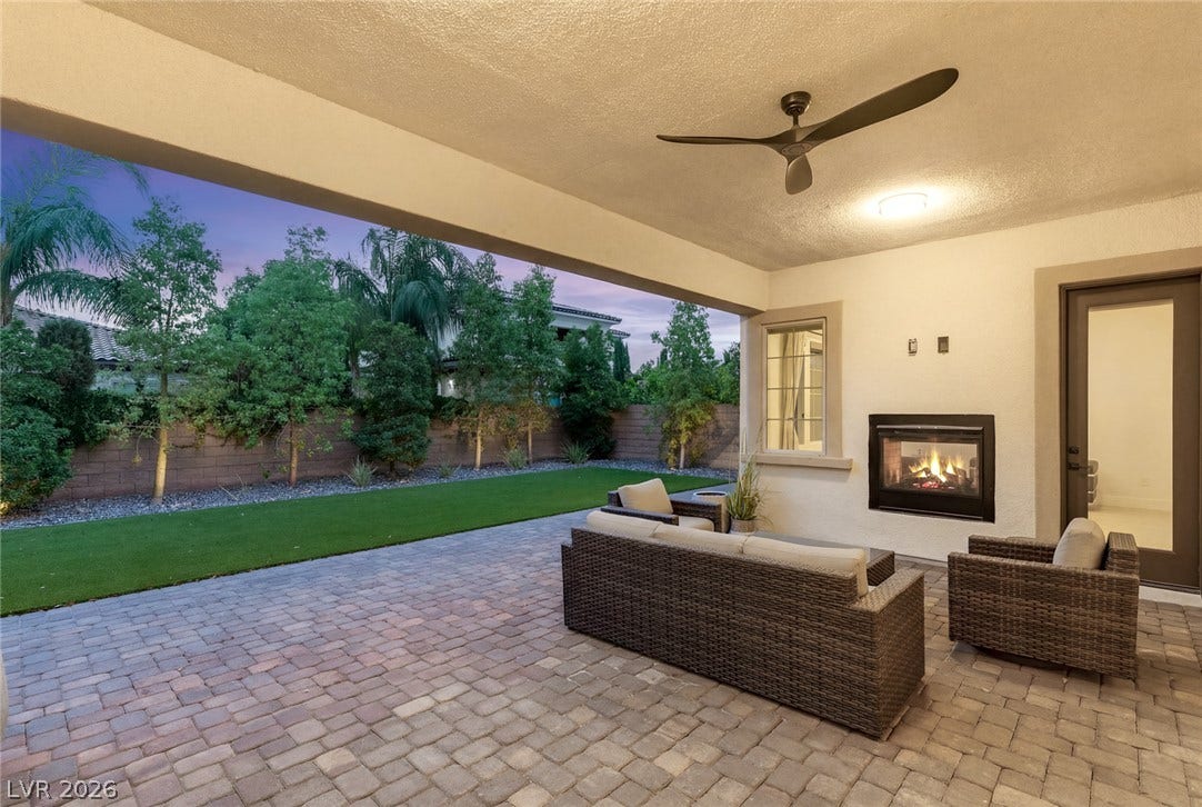 4078 San Franchesca Court, Las Vegas, NV 89141 An inviting outdoor living area features a fireplace and ceiling fan, perfect for evening relaxation.