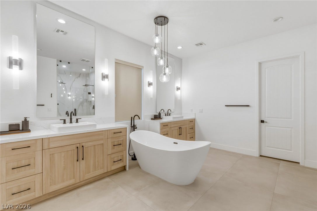 4078 San Franchesca Court, Las Vegas, NV 89141 A spacious primary bathroom showcases dual vanities, a luxurious soaking tub, and elegant tile flooring.