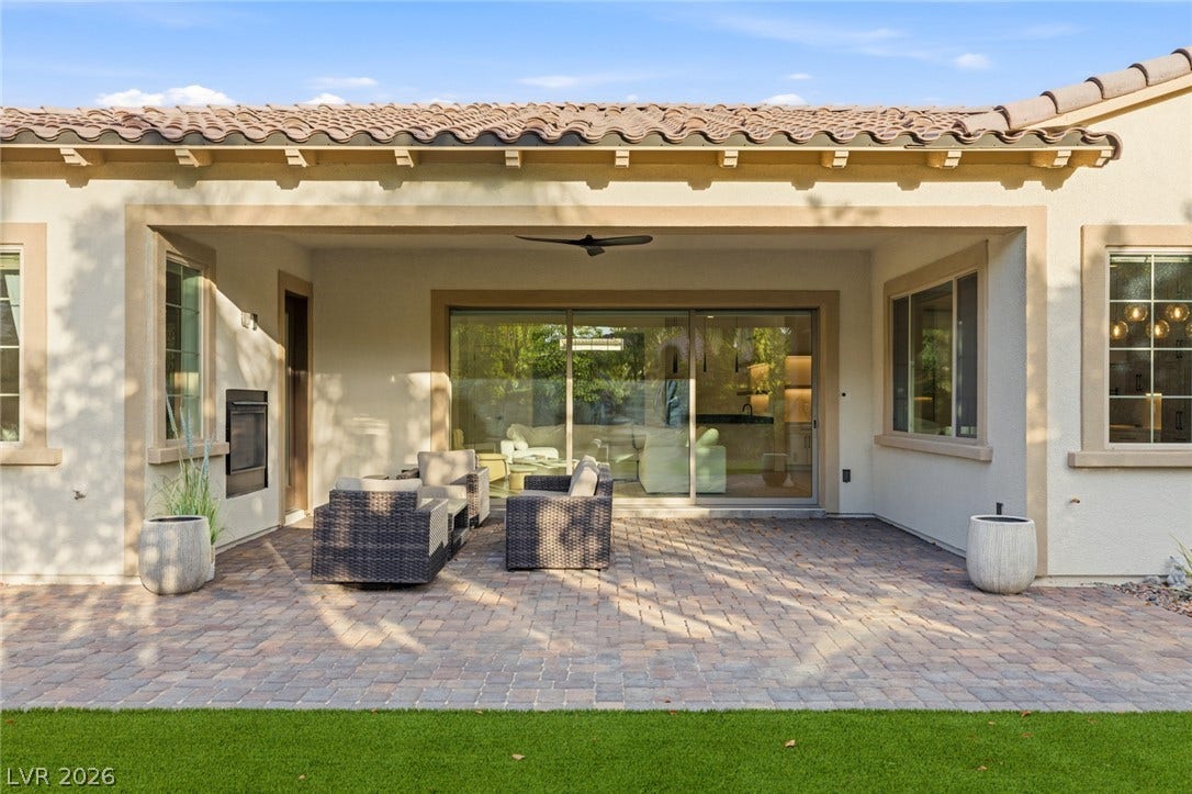 4078 San Franchesca Court, Las Vegas, NV 89141 A spacious covered patio with paver flooring extends to a lush green lawn, offering a perfect outdoor living space.
