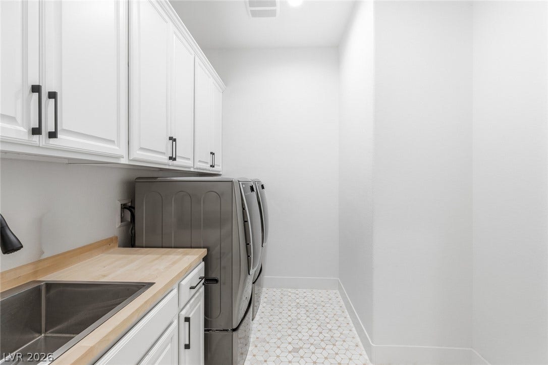 4078 San Franchesca Court, Las Vegas, NV 89141 A well-appointed laundry room features ample cabinetry, a utility sink, and modern appliances on patterned tile flooring.