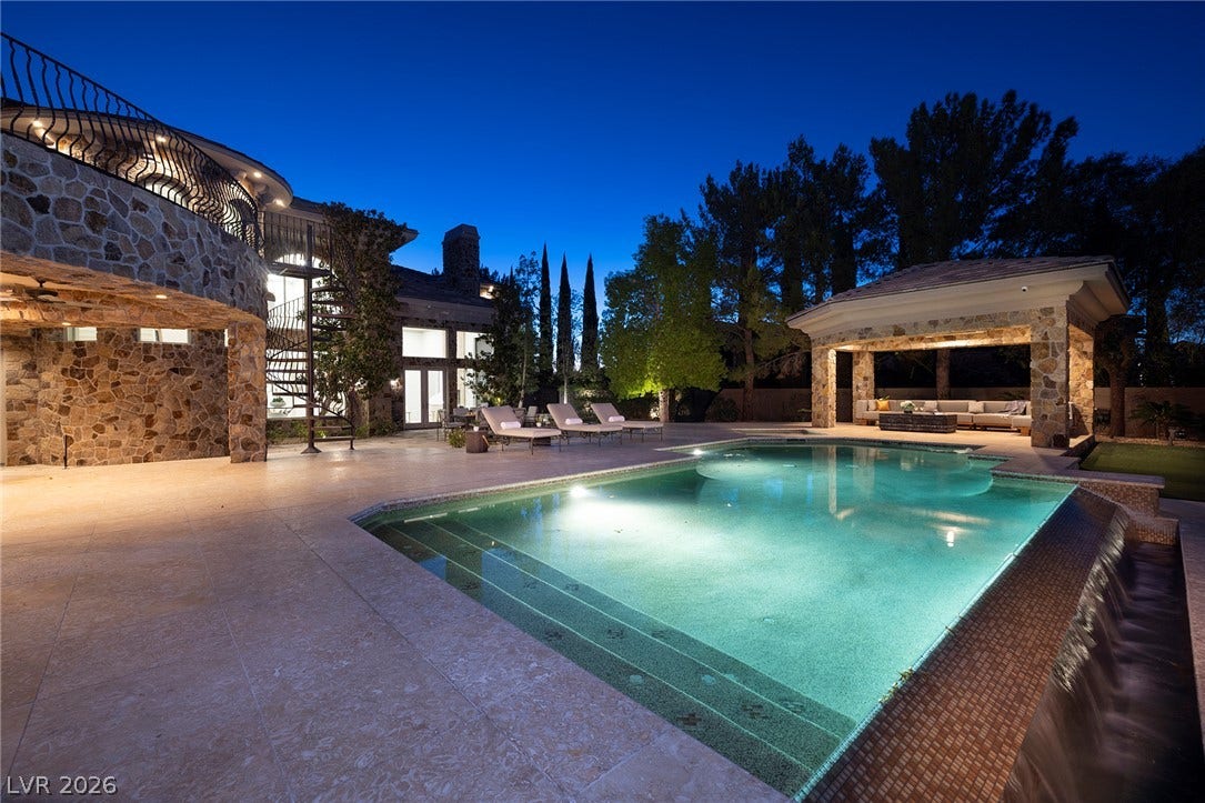 4 Ayden Drive, Henderson, NV 89052 An inviting backyard oasis features a shimmering pool alongside a stone pavilion and patio.