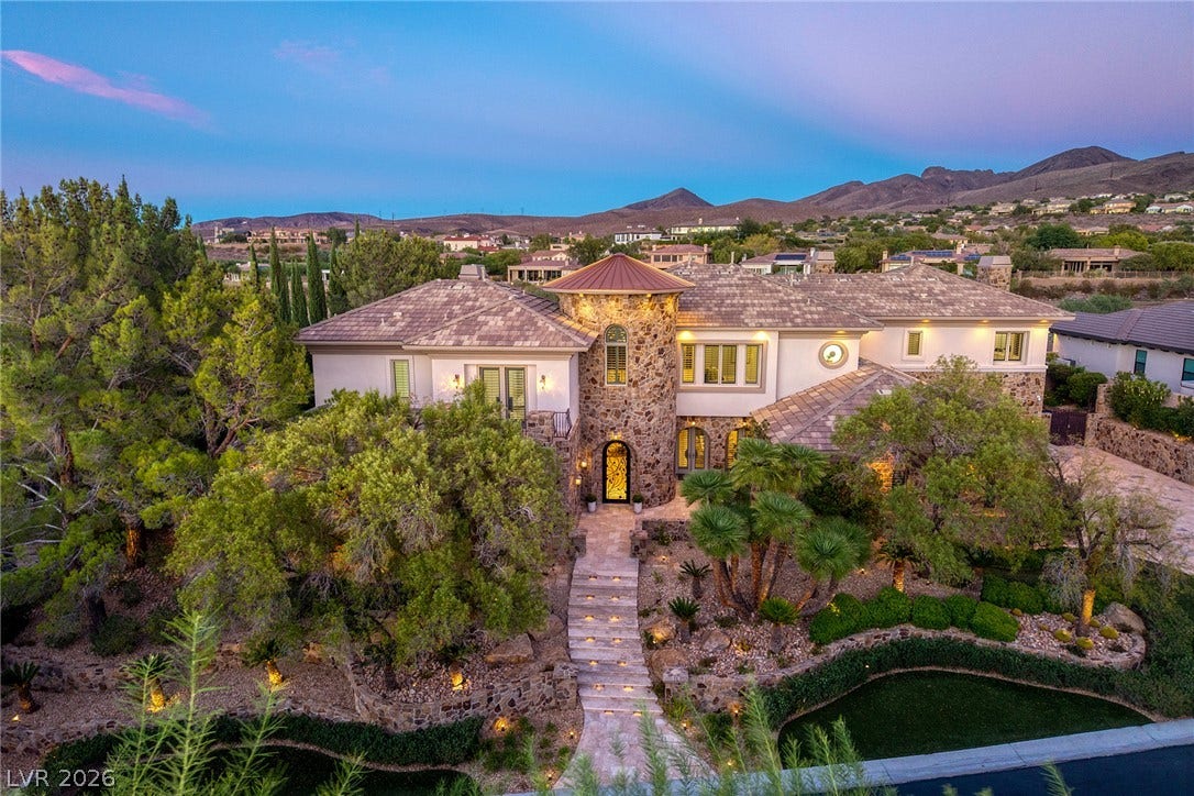 4 Ayden Drive, Henderson, NV 89052 A stone turret accents this grand desert estate flanked by mature trees and mountain backdrops.