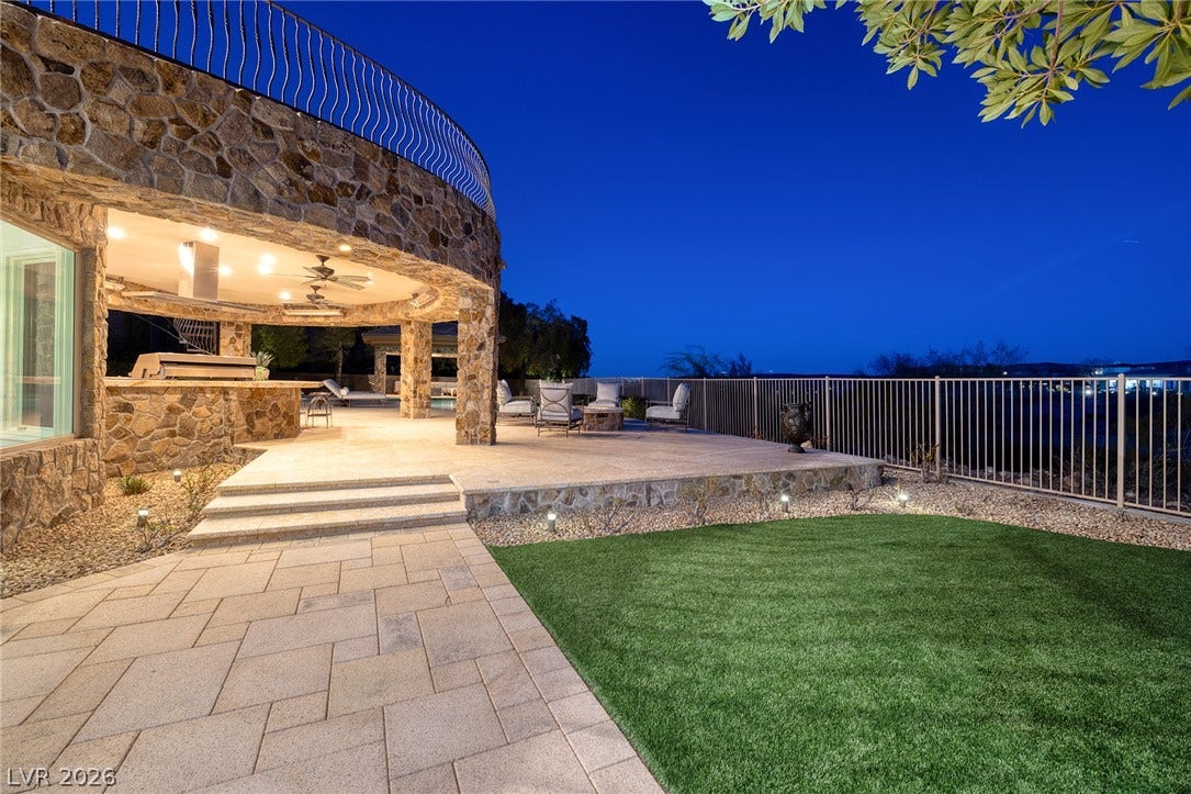 4 Ayden Drive, Henderson, NV 89052 Stone masonry accents a expansive patio overlooking manicured lawns under a deep twilight sky.